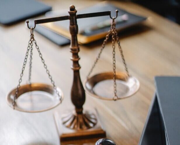 justice Decorative legal scales, bronze in color, sitting on top of a wooden desk.